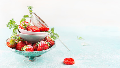 Bowls with fresh Strawberries and sugar strainer on light blue background, side view, banner