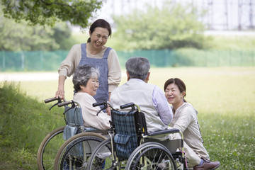 車椅子の夫婦とヘルパー