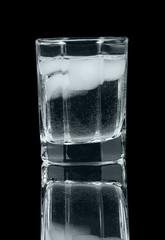 Glass of vodka with ice isolated on  black background.