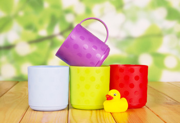 Colorful plastic cups and rubber duck on  green abstract background.