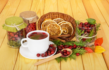 Autumn berries,   tea, slices  lemon, cinnamon on  background  light wood.