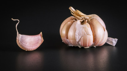 still life arrangement of Three whole garlic bulbs grouped on a black background.