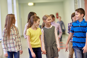 group of smiling school kids walking in corridor