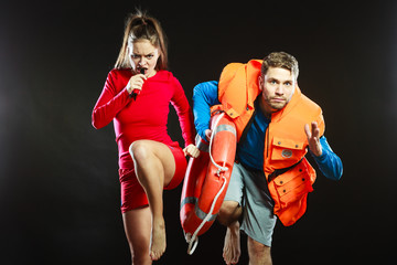 Lifeguards in life vest with ring buoy whistling.