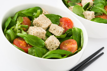 Vegan tofu salad with tomatoes and lamb's lettuce isolated on white background
