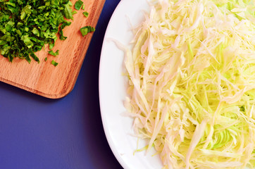 Sliced cabbage in a dish on the table. Chopped parsley and chopped cabbage