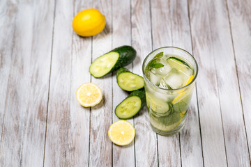 Water with lemon, mint and cucumber on wooden light background. Water Detox.