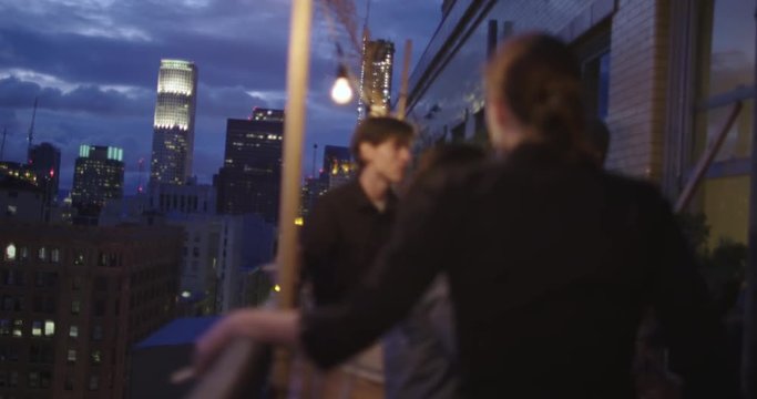 Focus on night skyline in Downtown Los Angeles, California, with party goers in soft focus in foreground.  Recorded in slow motion at 60fps.