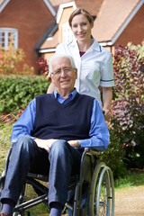 Portrait Of Carer Pushing Senior Man In Wheelchair