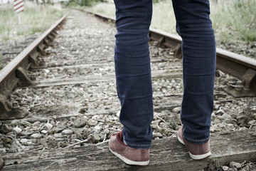 Close-Up Of Man's Feet Standing Between Railway Tracks