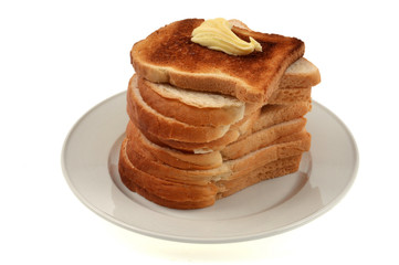 Assiette de tranches de pain de mie dont une toastée et beurrée