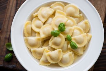 Glass plate with ravioli in bouillon, close-up, above view