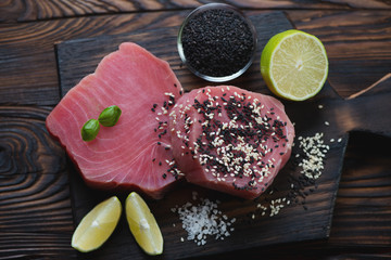 Raw fresh tuna steaks with condiments and sesame seeds, top view