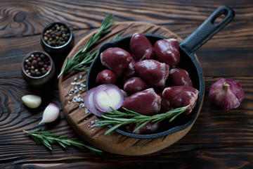 Frying pan with raw fresh turkey hearts and condiments