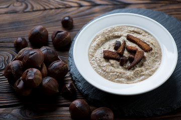 Glass plate with chestnut cream-soup and croutons, closeup