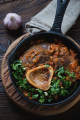 Close-up of ossobuco with gremolata in a cast-iron frying pan