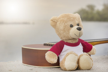 Ukulele and teddy bears on  river side in the evening.