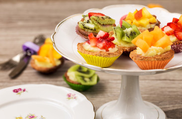 mini pastry with custard cream and fresh fruits over cake stand