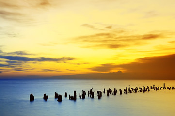 natural relaxation background. Romantic gentle morning sea. beautiful sunrise beautiful sky and clouds,  calm sea. Old ruined pier piles protruding from the surface of the sea. Long-term exposure.
