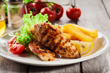 Grilled chicken breasts served with fries and fresh salad