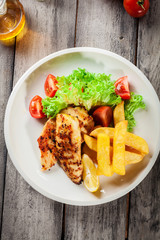Grilled chicken breasts served with fries and fresh salad