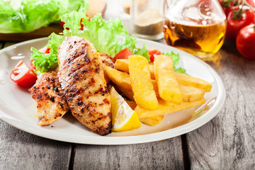 Grilled chicken breasts served with fries and fresh salad