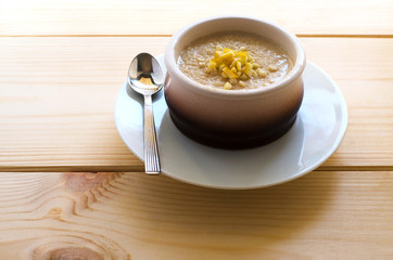 Homemade rice pudding in a ceramic bowl with lemon on wooden background. Delicious healthy dessert.