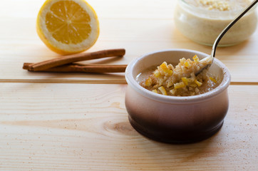 Homemade rice pudding in a ceramic bowl with sticks of cinnamon and lemon on wooden background. Delicious healthy dessert.