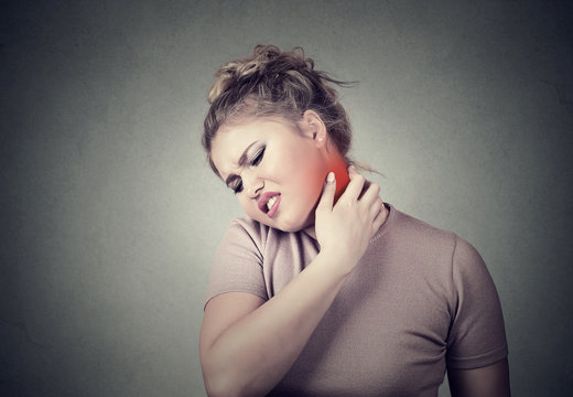 young woman massaging her painful neck colored in red