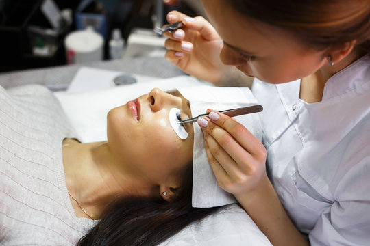 eyelash extension procedure - master and a client in a beauty salon