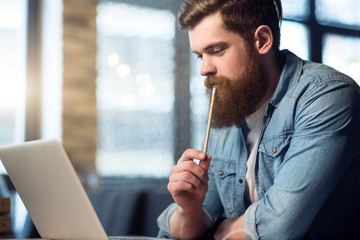 Concentrated bearded man sitting at the table   