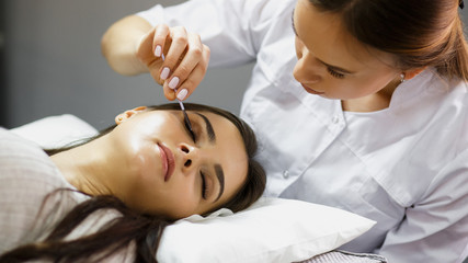 Obraz na płótnie Canvas eyelash extension procedure - master and a client in a beauty salon