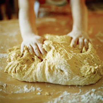 A child kneading a dough.
