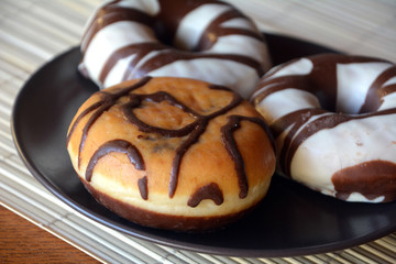 Traditional  donuts  with brown chocolate on the plate on the table