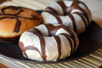 Traditional  donuts  with brown chocolate on the plate on the table