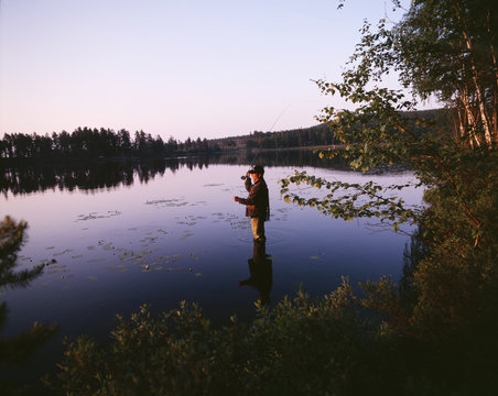 Man standing i sea, fishing, Sweden.