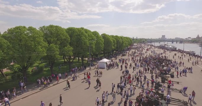 Aerial view of people walking along  river bank and military machines in Gorky Park in Moscow on a sunny spring day. Celebration of the Victory Day.  