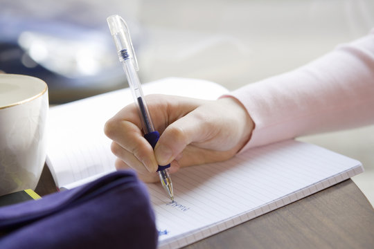 A girl writing in her note book in a cafe.