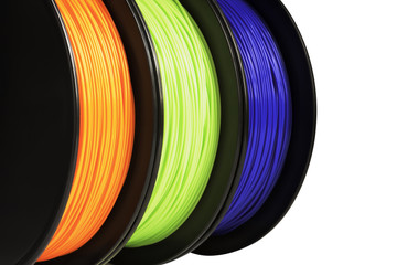 Filament for 3d printing. Bright termoplastic of neon orange, green and blue colors. Isolated on white background. Material produced from polylactic (pla) acid. Three reels vertical view. Macro