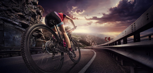 Sport. Cyclist riding a bike on an open road to the sunset

