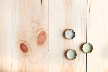 Fototapeta premium three caps from beer on a wooden board, top view
