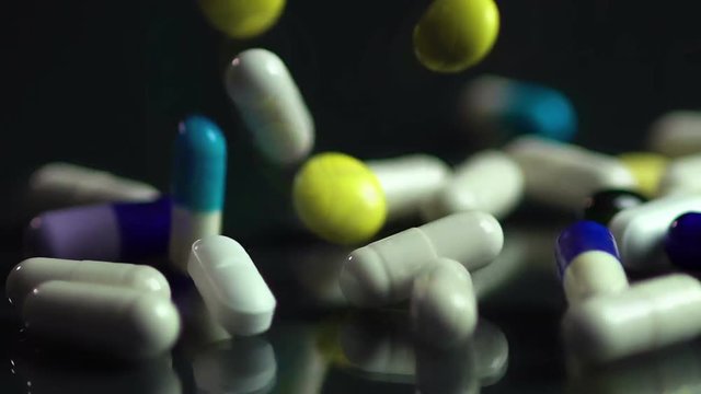 Many tablets and capsules dropping, pharmaceutical industry, medication closeup