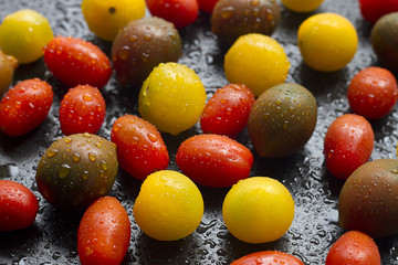 Variety of cherry tomatoes on black background.