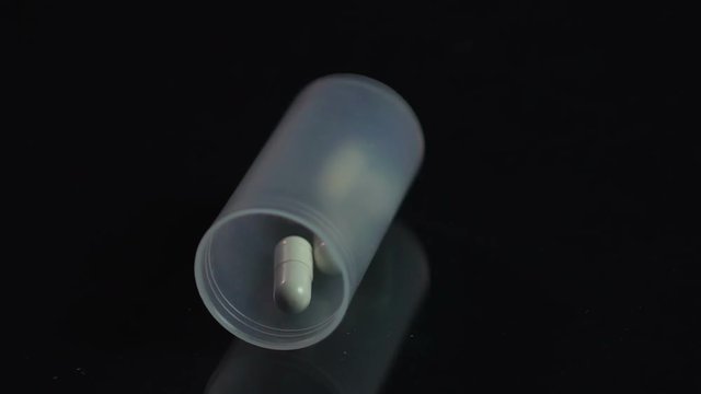Pharmacy container with capsules falling, patient's response to bad diagnosis