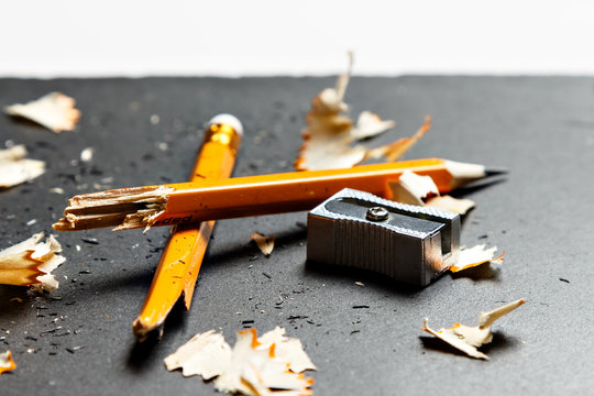 Broken pencil with metal sharpener and shavings.