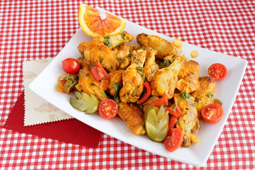 Braised chicken wings with orange and pickled cucumber.