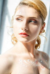 Beautiful blonde young girl with perfect makeup and hair style in elegant interior