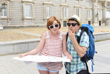 young tourist couple visiting Europe reading city map looking lost and confused loosing orientation