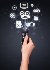 Hand with remote control and media icons