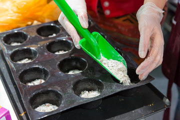 Woman putting dough in forms for baking